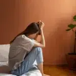 woman on bed with hands in head